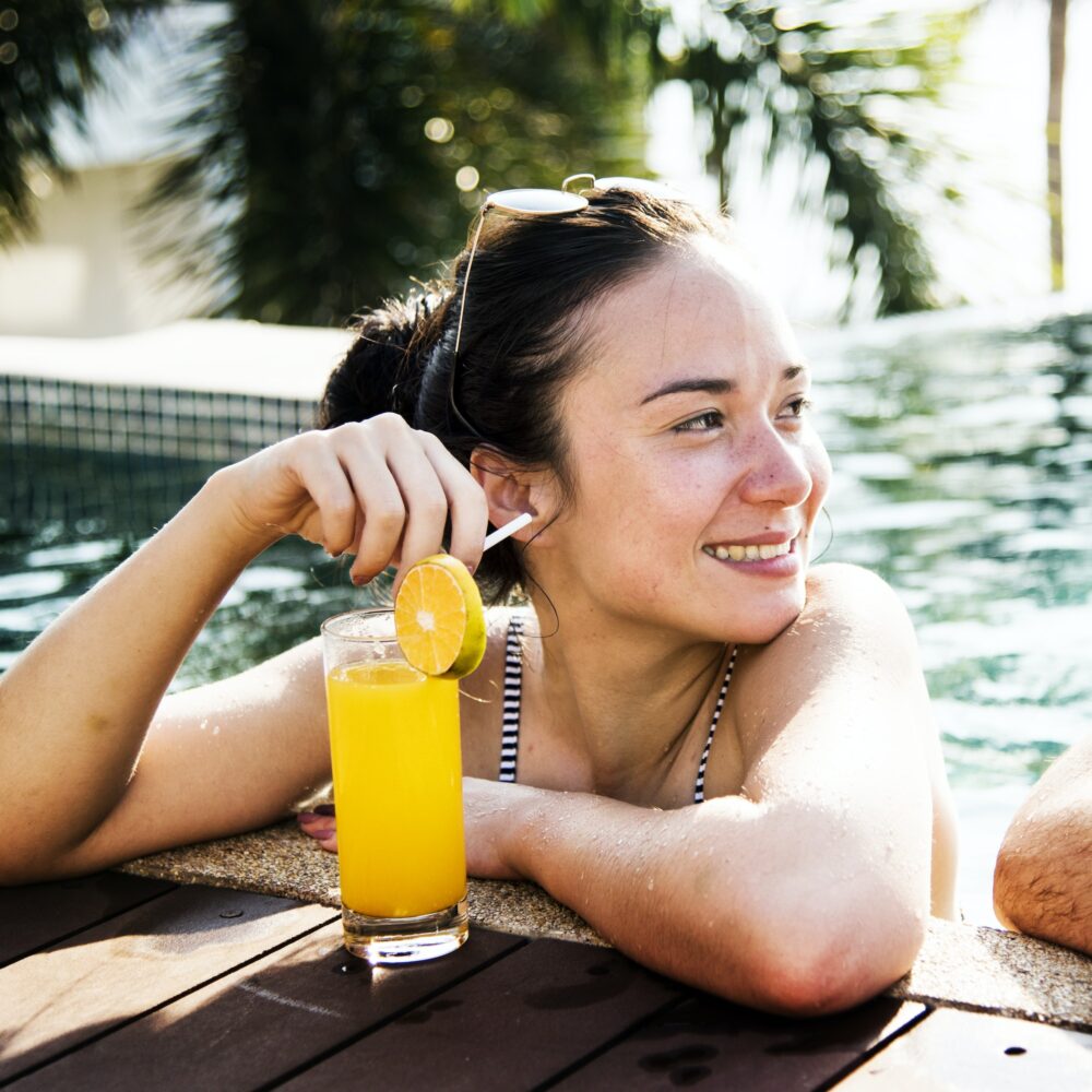 A woman in a pool with an orange juice