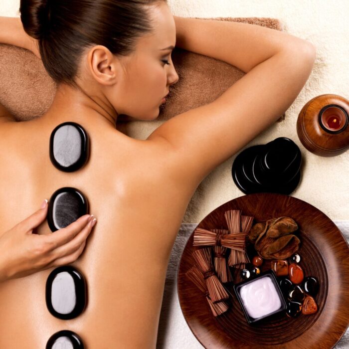 Young woman getting hot stone massage in spa salon.